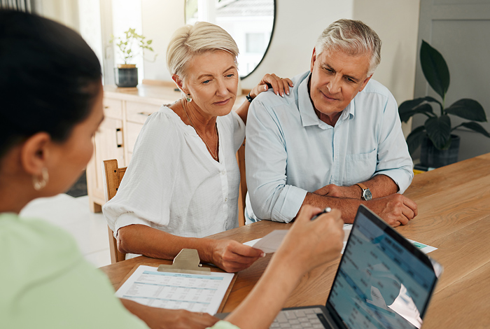 Frau erklärt älterem Ehepaar zu Hause Pflegeleistungen
