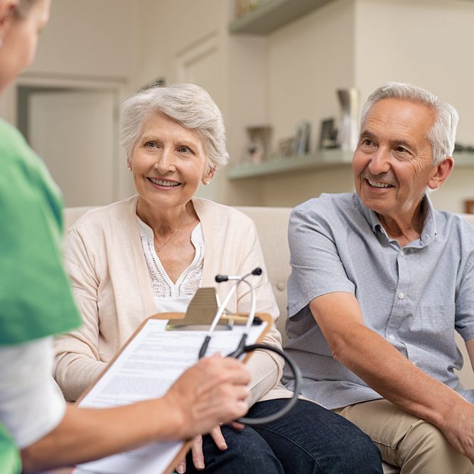 Pflegerin mit älterem Ehepaar im Wohnzimmer - Schritt 2 - Beratungsgespräch